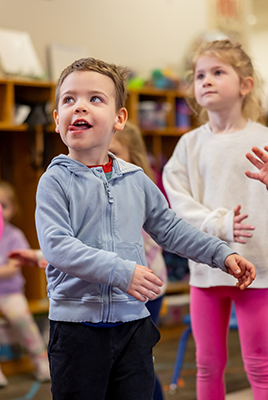 young boy dances with other children in a classroom